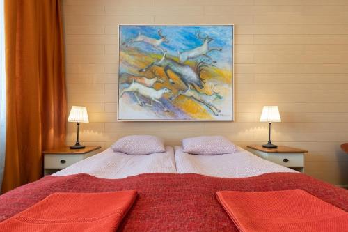 a bedroom with a bed with a painting on the wall at Rovaniemi City Apartments in Rovaniemi