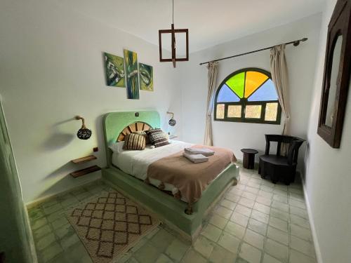 ein Schlafzimmer mit einem Bett und einem Buntglasfenster in der Unterkunft Villa nouran in Ghazoua