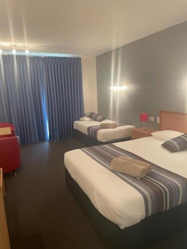 a hotel room with three beds and a window at William Dutton Motel in Portland