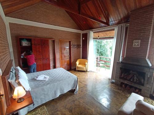 a person in a room with a bed and a fireplace at Chalé Recanto do Sol in Paraisópolis