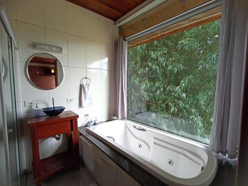 a bathroom with a tub and a large window at Chalé Recanto do Sol in Paraisópolis