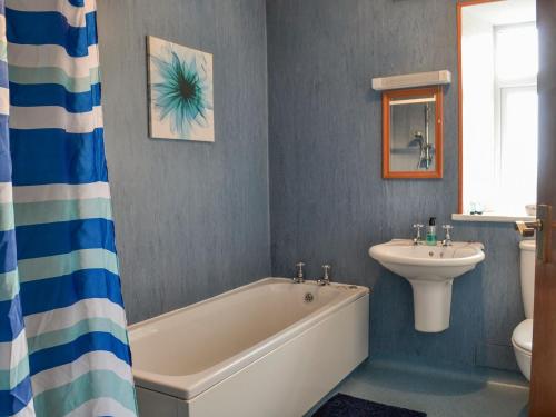 a bathroom with a bath tub and a sink at Airdside Cottage in Crossmichael