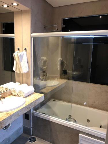 a bathroom with a shower and a sink and a tub at San Raphael Hotel in Sao Paulo