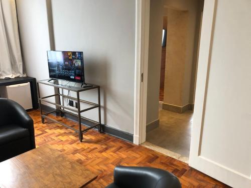 a living room with a television and a table with a chair at San Raphael Hotel in Sao Paulo