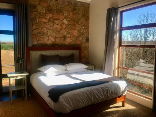 a bedroom with a bed and a stone wall at Vetho Farmhouse Dullstroom in Dullstroom