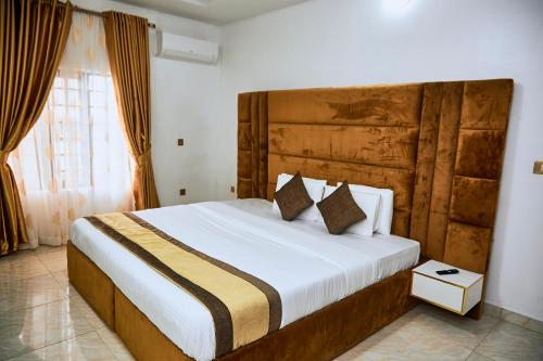 a bedroom with a large bed with a wooden headboard at 247 Luxury Hotel & Apartment Ajah in Lekki