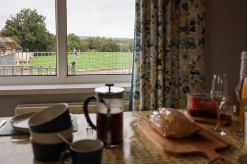 a kitchen table with a window with a view of a pasture at Benbradagh Country Cottage Causeway Coast in Dungiven