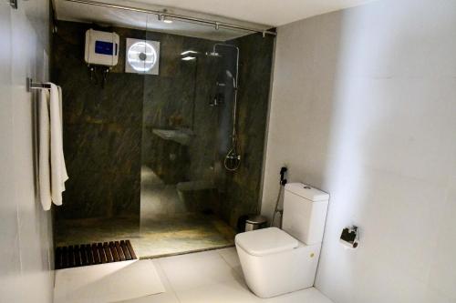 a bathroom with a shower and a white toilet at Ten30 Hikkaduwa in Hikkaduwa