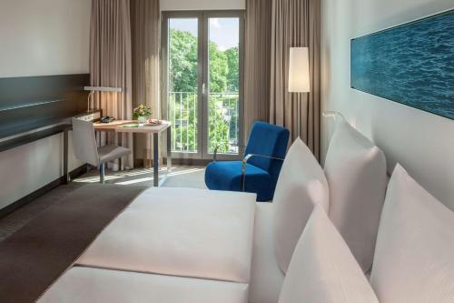 Cette chambre comprend un lit et un bureau. dans l'établissement Dorint Hotel Hamburg-Eppendorf, à Hambourg