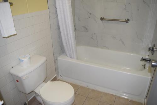 a bathroom with a white toilet and a tub and a sink at White Oaks Motel Pennsville/Carneys Point in Pennsville