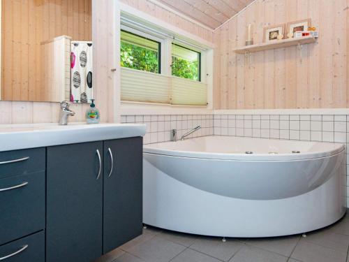 a bathroom with a tub and a sink at Three-Bedroom Holiday home in Glesborg 28 in Fjellerup Strand