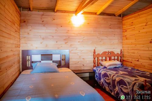 two beds in a room with wooden walls at Villa Maria in Guatavita