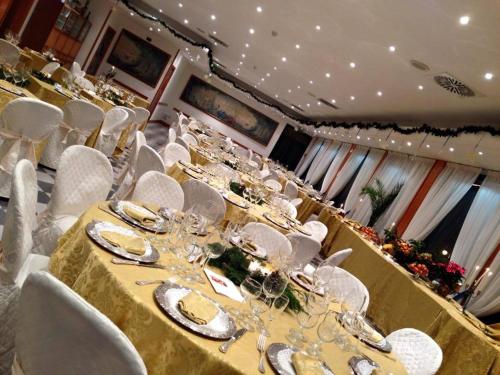 a dining room with a long table and white chairs at Platani Hotel in Bolsena