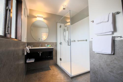 a bathroom with a shower and a sink and a mirror at Scenic Hotel Cotswold in Christchurch