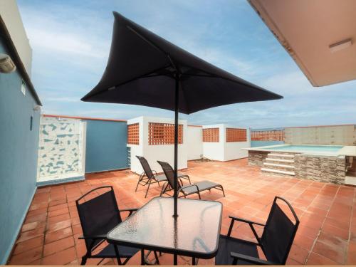 韋拉克魯斯的住宿－Hotel Meson del Barrio，庭院配有椅子和桌子及遮阳伞