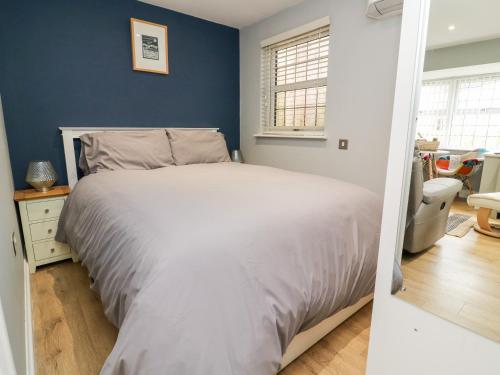 a bedroom with a white bed and a blue wall at Robin Cottage in Beverley