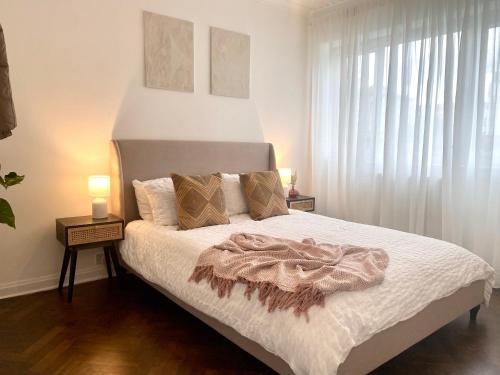 a bedroom with a bed with white sheets and a window at Newly refurbished 2 BR Apartment in South London in London