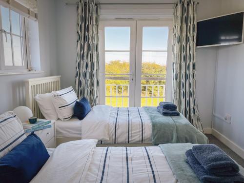 a bedroom with two beds and a window with curtains at Marine House in Camber