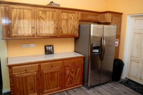 a kitchen with a stainless steel refrigerator and wooden cabinets at Glasgow Villa at La Mar in Laborie