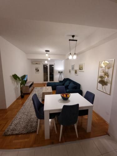 een woonkamer met een witte tafel en blauwe stoelen bij Big apartment in Podgorica