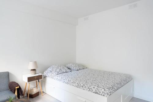 a white bedroom with a bed and a white wall at Spacious studio in the center of Montmartre in Paris