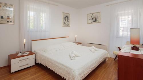 a white bedroom with a white bed and two lamps at Seaside house for families with children Sutivan, Brac - 20131 in Sutivan