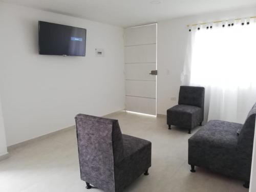 uma sala de estar com 2 cadeiras e uma televisão de ecrã plano em Hermoso apartamento nuevo primer piso em San Gil