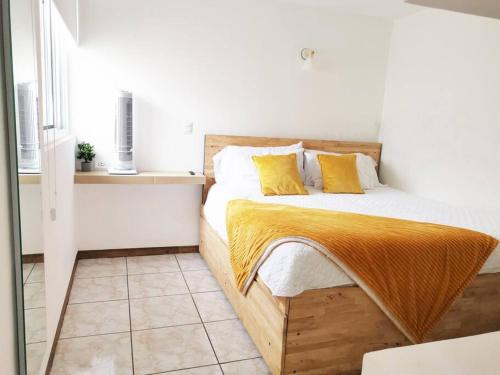 um quarto com uma cama de madeira e almofadas amarelas em Immaculate apartment G1 em Guatemala