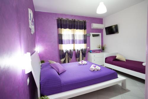 a purple bedroom with two beds and a mirror at B&B Pepito in Cefalù