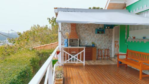 a deck with a white umbrella and a kitchen at Pousada Araucária Suítes in Campos do Jordão