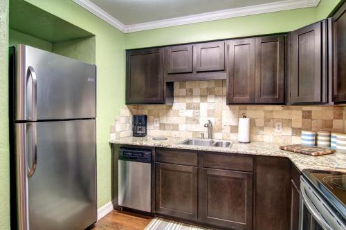 a kitchen with wooden cabinets and a stainless steel refrigerator at Sand In Your Toes in Mustang Beach