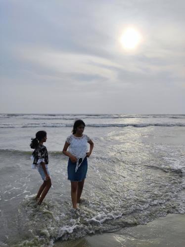 two women standing in the water on the beach at SuKun Heritage in Kannur