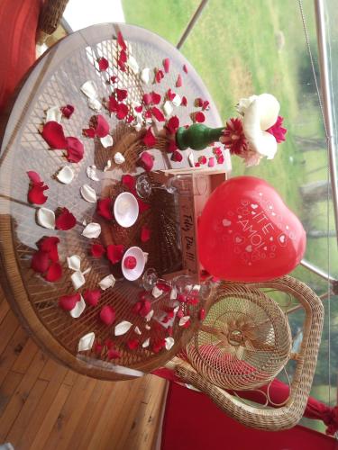 a glass table with red flowers and a red mushroom at Glamping Mi Casita in Guatavita
