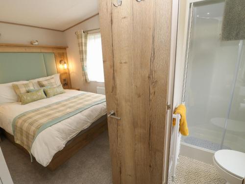 a bedroom with a bed and a bathroom with a shower at 10 Cheviot View in Berwick-Upon-Tweed