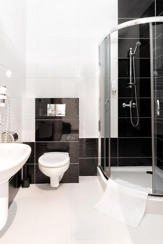 a bathroom with a shower and a toilet and a sink at Hotel Pogoria Residence in Dąbrowa Górnicza