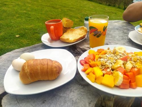 una mesa con platos de comida y un vaso de zumo de naranja en Glamping Mi Casita, en Guatavita