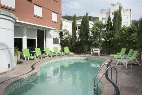 a swimming pool with green lounge chairs at Hosteria Los Tilos in Villa Carlos Paz
