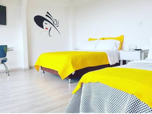 two beds in a room with yellow covers on them at Santelmo Casa Hotel Boutique in Paipa