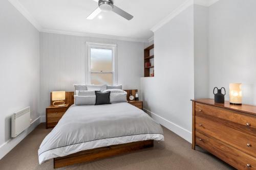 a bedroom with a bed and a dresser and a window at The SCOOP in Queenscliff