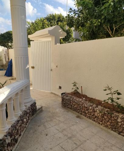 a white fence with a gate and a stone wall at Tiba soliman plage in Nabeul