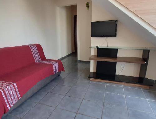 uma sala de estar com um sofá e uma televisão de ecrã plano em Apartamento super arejado na Praia do Morro em Guarapari