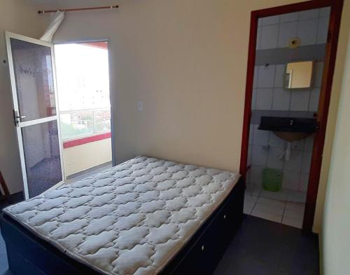 a small bedroom with a bed and a bathroom at Apartamento super arejado na Praia do Morro in Guarapari