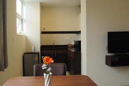 a room with a table with a vase with a flower at Ixora Suites in Bengaluru