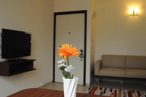 a vase of flowers in a living room with a couch at Ixora Suites in Bengaluru