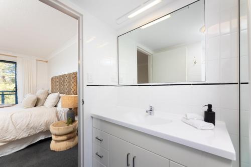 a white bathroom with a sink and a mirror at Spinnaker 201 in Forster