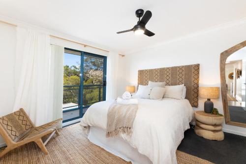 a white bedroom with a bed and a window at Spinnaker 201 in Forster