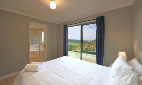 a bedroom with a bed and a large window at The Roost in Johanna
