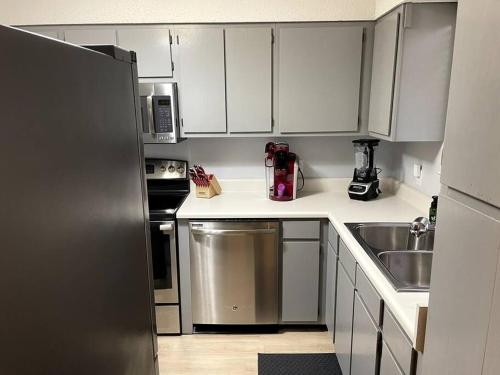 a kitchen with white cabinets and a stainless steel refrigerator at Modern 2 Bedroom Townhome Minutes from the Beach!! in Fort Walton Beach
