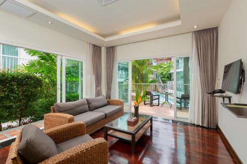 Phunawa Resort Phuket Karon Beach - SHA Plus في شاطئ كارون: غرفة معيشة مع أريكة وطاولة