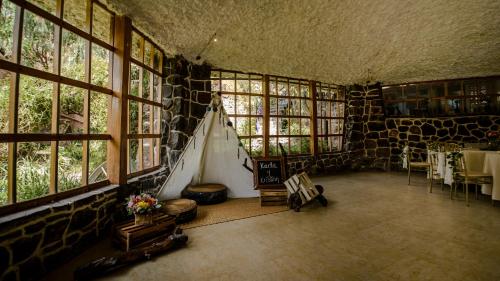 Habitación grande con ventanas, mesa y sillas. en Eco Tampu Andahuaylillas- Hospedaje Ecosostenible, en Andahuaylillas